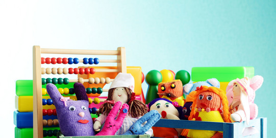 Bunte Handpuppen und Quietscheentchen vor einem Rechenschieber und Bauklötzen.